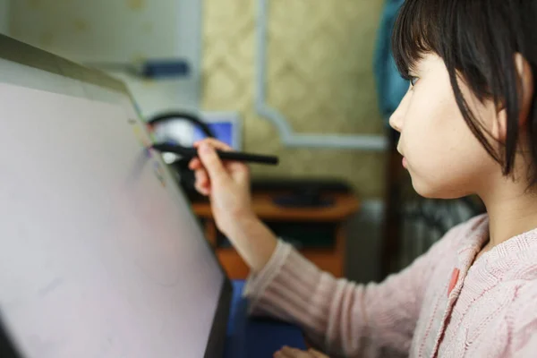 Menina bonito se baseia em um tablet gráfico . — Fotografia de Stock