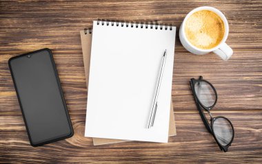 Kalemli defter, akıllı telefon, bardak ve kahve..