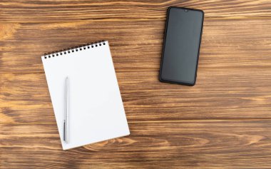 Kalemli defter, ahşap arkaplanda akıllı telefon.