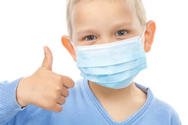 의료용 마스크를 쓰고 있는 어린이가 엄지손가락을 내밀고 있다. — 스톡 사진