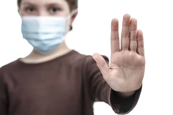 A criança na máscara médica pôs uma palma no sinal de parada . — Fotografia de Stock