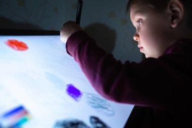 Çocuk akşamları grafik tablet çiziyor..