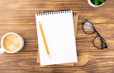 Kalem, bitki, bardak ve kahve içeren defter.