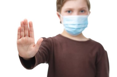 Tıbbi maskeli çocuk dur işaretine avuç içi koymuş..