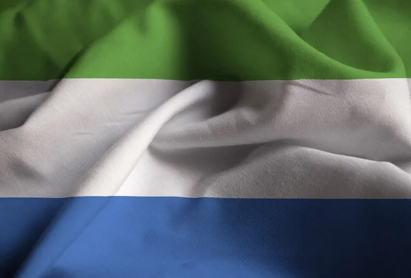 Primer plano de la bandera de Sierra Leona con volantes, bandera de Sierra Leona soplando en el viento — Foto de Stock