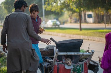 İslamabad, İslamabad Başkent Bölgesi, Pakistan - 2 Şubat 2020, genç çocuklar müşteriler için taze mısır kızartıyorlar.