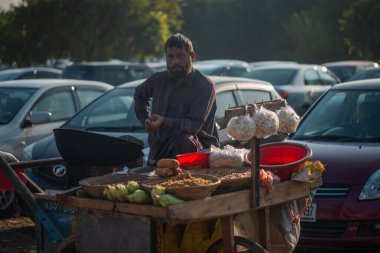 İslamabad, İslamabad Başkent Bölgesi, Pakistan - 2 Şubat 2020, Bir adam taze kavrulmuş mısır, patlamış mısır, tatlı mısır ve sokakta kızarmış nohut satıyor..
