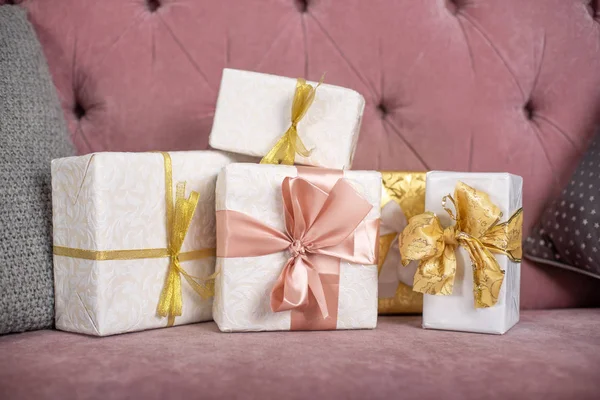 ピンクのソファの背景にクリスマスプレゼント付き4箱 — ストック写真