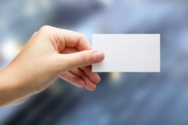 Holding bir beyaz iş ziyaret kimlik kartı, hediye, Bilet, pass eller, mevcut yakın Tarih gösteren mavi arka plan bulanık. Kopya alanı reklam metni için