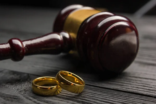 Scheidings- en scheidingsconcept. Twee gouden trouwringen, rechter hamer — Stockfoto