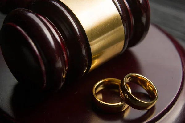 Scheidings- en scheidingsconcept. Twee gouden trouwringen, rechter hamer — Stockfoto
