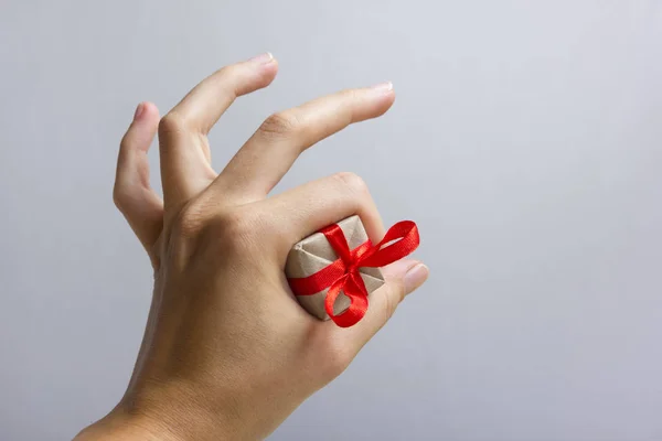 Female hand holding present gift box against grey background. Happy family celebrating concept for Valentine Birthday Christmas or New Years day — Stock Photo, Image