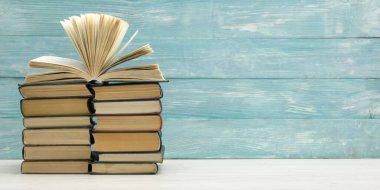 Kaliteli eski ciltli kitaplar, günlük ahşap güverte masasında ve kırmızı arka planda sayfaları olan kompozisyon. Kitaplar istifleniyor. Okula dönelim. Uzayı kopyala Eğitim geçmişi.