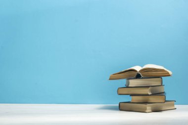Kaliteli eski ciltli kitaplar, günlük ahşap güverte masasında ve kırmızı arka planda sayfaları olan kompozisyon. Kitaplar istifleniyor. Okula dönelim. Uzayı kopyala Eğitim geçmişi.