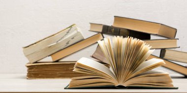 Kaliteli eski ciltli kitaplar, günlük ahşap güverte masasında ve soyut arka planda sayfaları olan kompozisyon. Kitaplar istifleniyor. Okula dönelim. Uzayı kopyala Eğitim geçmişi.