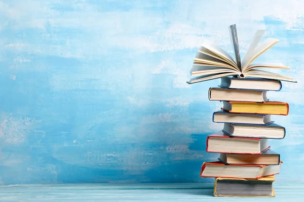 Composition with vintage old hardback books, diary, fanned pages on wooden deck table and abstract background. Books stacking. Back to school. Copy Space. Education background.