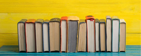 Composition with vintage old hardback books, diary, fanned pages on wooden deck table and abstract background. Books stacking. Back to school. Copy Space. Education background.