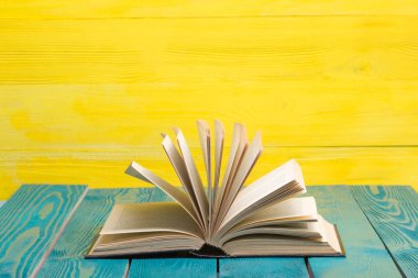 Kaliteli eski ciltli kitaplar, günlük ahşap güverte masasında ve kırmızı arka planda sayfaları olan kompozisyon. Kitaplar istifleniyor. Okula dönelim. Uzayı kopyala Eğitim geçmişi.