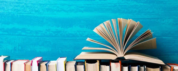 Composition with vintage old hardback books, diary, fanned pages on wooden deck table and abstract background. Books stacking. Back to school. Copy Space. Education background.