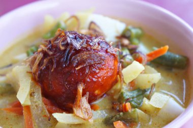 Lontong sayur ya da sebze yahnili pirinç keki hindistan cevizi sütü ve kızarmış arpacık soğanı ve sarımsak ile süslenmiş soğuk ve haşlanmış yumurtayla kaplanmış karides ezmesi.. 