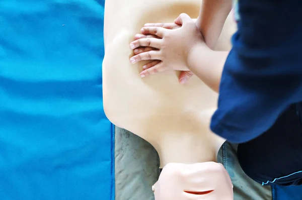 Young person learning to perform CPR first aid t on a test dummy. CPR is an emergency procedure that combines chest compressions on a person who is in cardiac arrest.