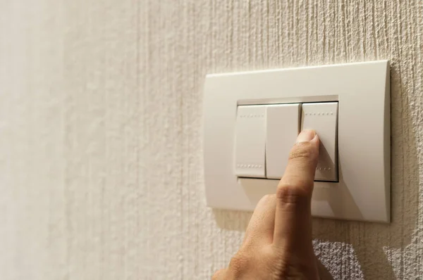 Closeup of A finger is turning on a lighting switch.