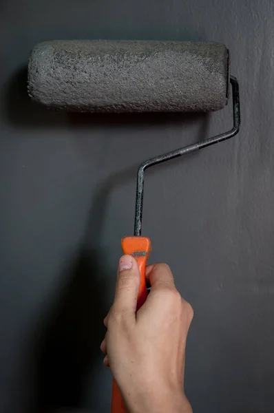 Primo piano della mano con rullo di vernice che applica vernice grigia sulla parete . — Foto Stock