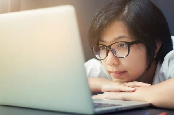 Азиатская девушка улыбается и смотрит на свой ноутбук . — стоковое фото