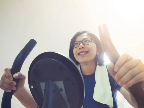 Close-up van Aziatische vrouw uit te werken op hometrainer. — Stockfoto