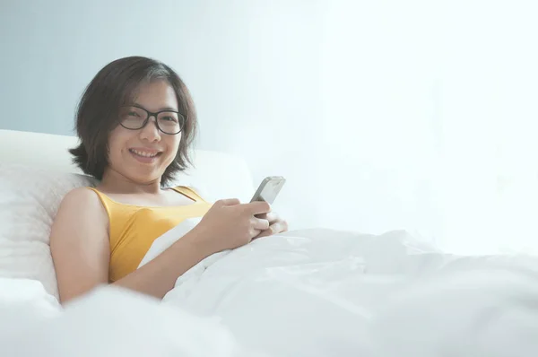 Asiatique femme couché avec smartphone sur le lit . — Photo