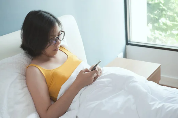 Asiatique femme couché avec smartphone sur le lit . — Photo