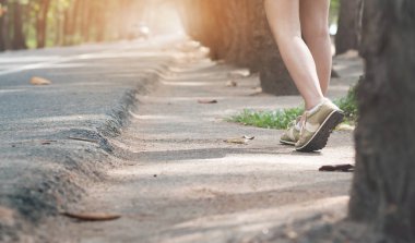 Güneş ışığı ile karayolu yolda yürüyen kadın otostopçu.