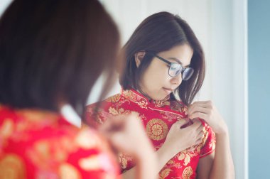 Asya gözlük kadın onun cheongsam ayna ile seyir.