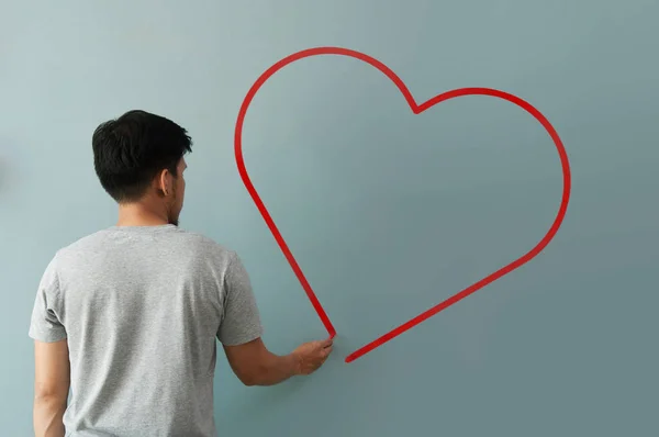 Hombre dibujando corazón para el día de San Valentín con tiza roja en la pared . — Foto de Stock