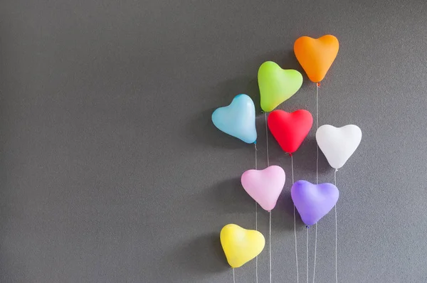 Globos multicolores en forma de corazón sobre fondo gris . — Foto de Stock