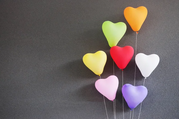 Globos multicolores en forma de corazón sobre fondo gris . — Foto de Stock
