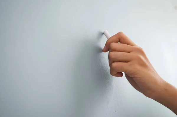 Vrouw hand tekenen met wit krijt op de muur. Close-up. — Stockfoto