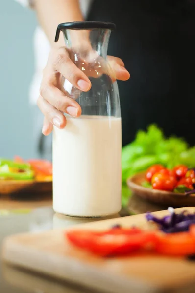 Жінка рука тримає пляшку молока з овочами . — стокове фото