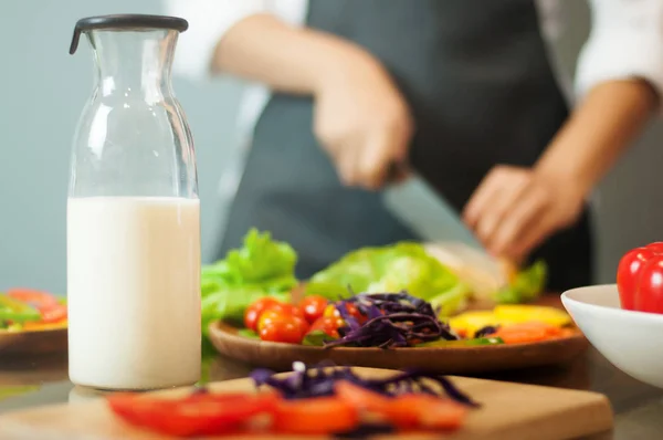 Молоко в пляшці з жінкою приготування їжі та овочів . — стокове фото