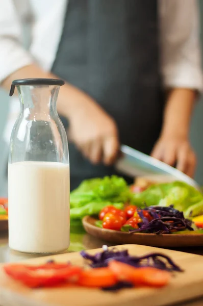 Молоко в пляшці з жінкою приготування їжі та овочів . — стокове фото