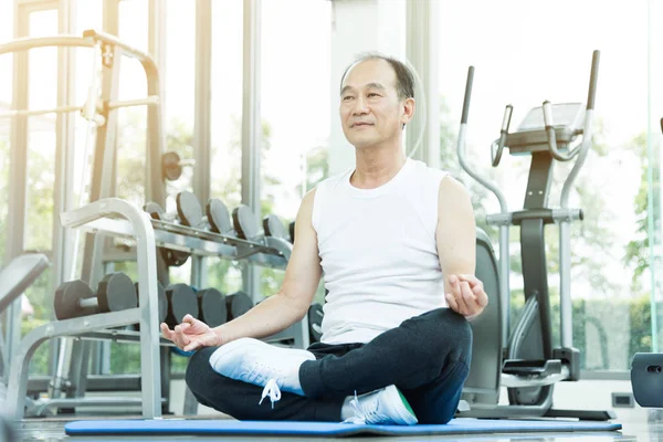 Asian senior man practicing yoga. Copy space. Meditating