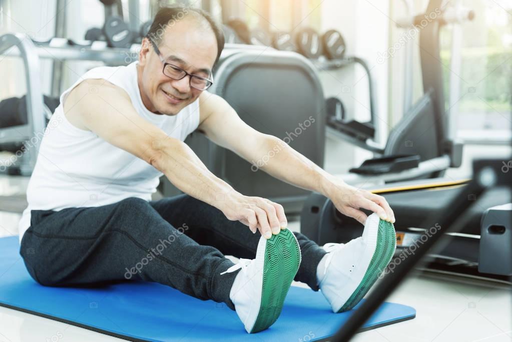Asian senior man Stretching before workout at the gym. copy spac