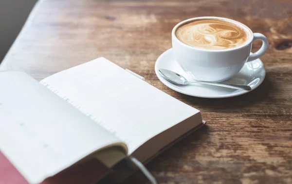Offenes Notizbuch mit Tasse Kaffee auf Holztisch. — Stockfoto