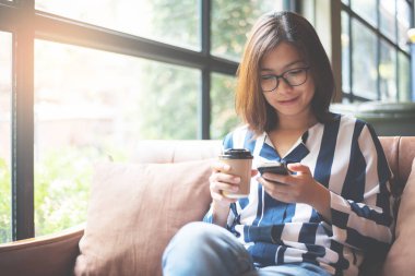 Asyalı kadın cep telefonu kullanarak rahat. Mutluluk gözlük kız 