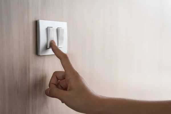 Fechar a mão ligando ou desligando no interruptor de luz cinza com madeira — Fotografia de Stock