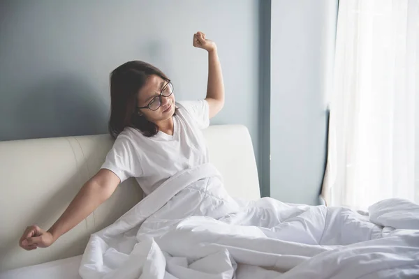 Asiatische Frau wacht am Morgen auf. Ausgestreckte Arme. — Stockfoto