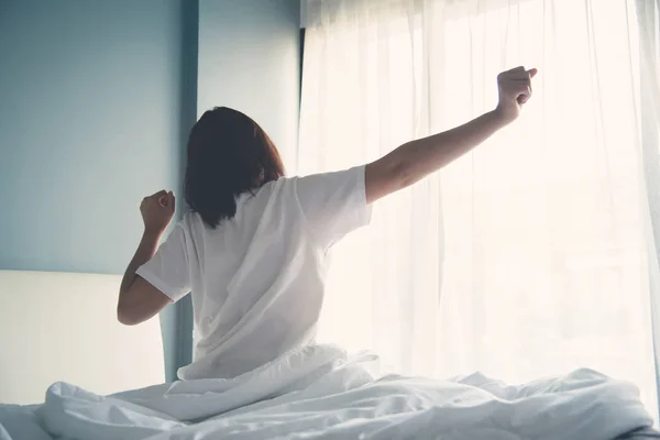 Asiatische Frau wacht am Morgen auf. Ausgestreckte Arme. — Stockfoto