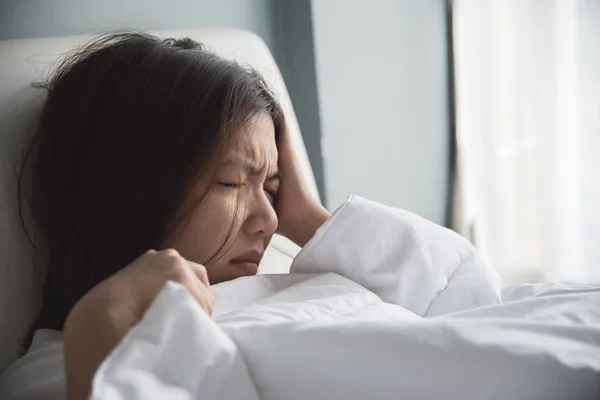 Mulher asiática com dor de cabeça em sua cama. Enxaqueca . — Fotografia de Stock