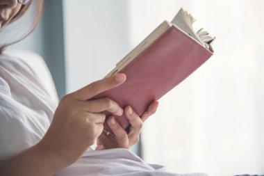 Asyalı kadın onun yatağında bir kitap okuma.