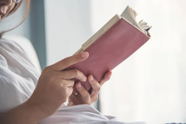 Asiatische Frau liest ein Buch auf ihrem Bett. — Stockfoto